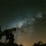 Silhouette of a telescope with a stunning Milky Way background in the night sky.